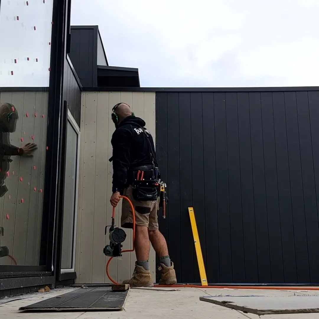 Carpenter on site installing cladding on a modern build