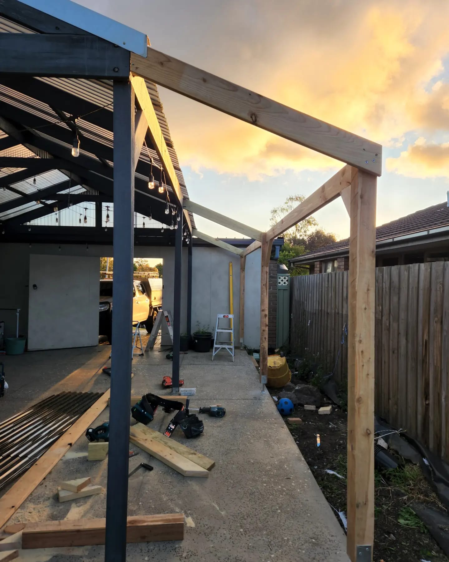 Pergola under construction with steel and pine timber framing at sunset